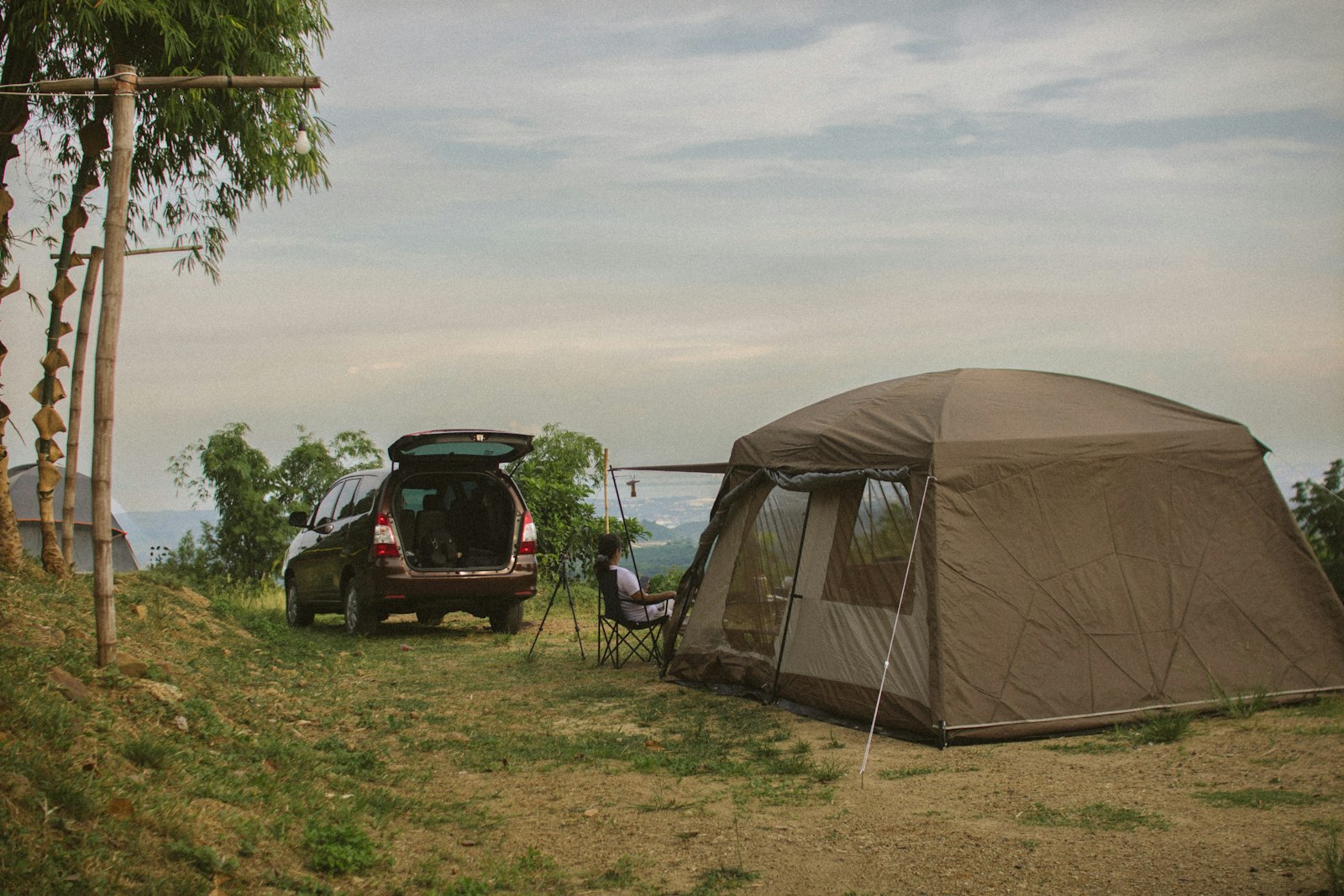 A car parked next to a ground tent in an open field