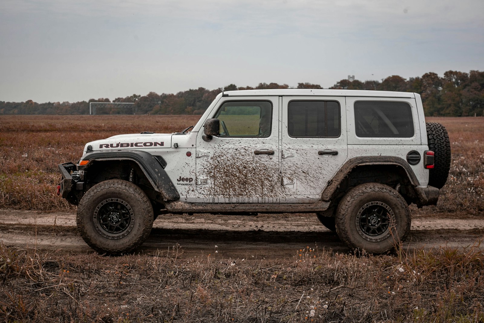 A mud-splattered Jeep Wrangler on a dirt trail